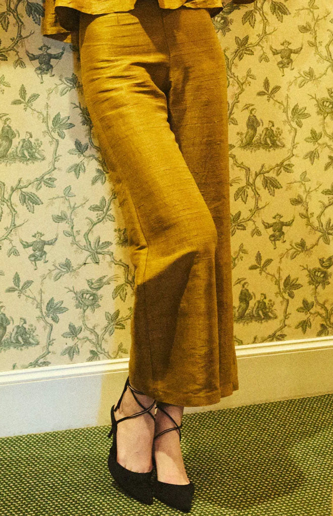 Cropped front view of Libby Pant in ochre showing high waist and cropped straight leg in textured fabric against floral wallpaper