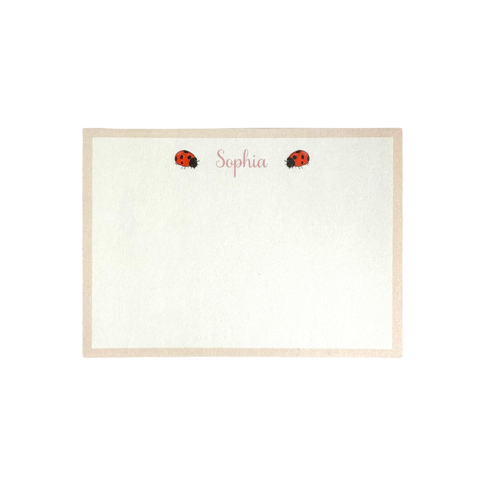 Flat lay of Ladybird Notecard showing personalized name Sophia in pink script and two ladybug illustrations with a beige border on a white background