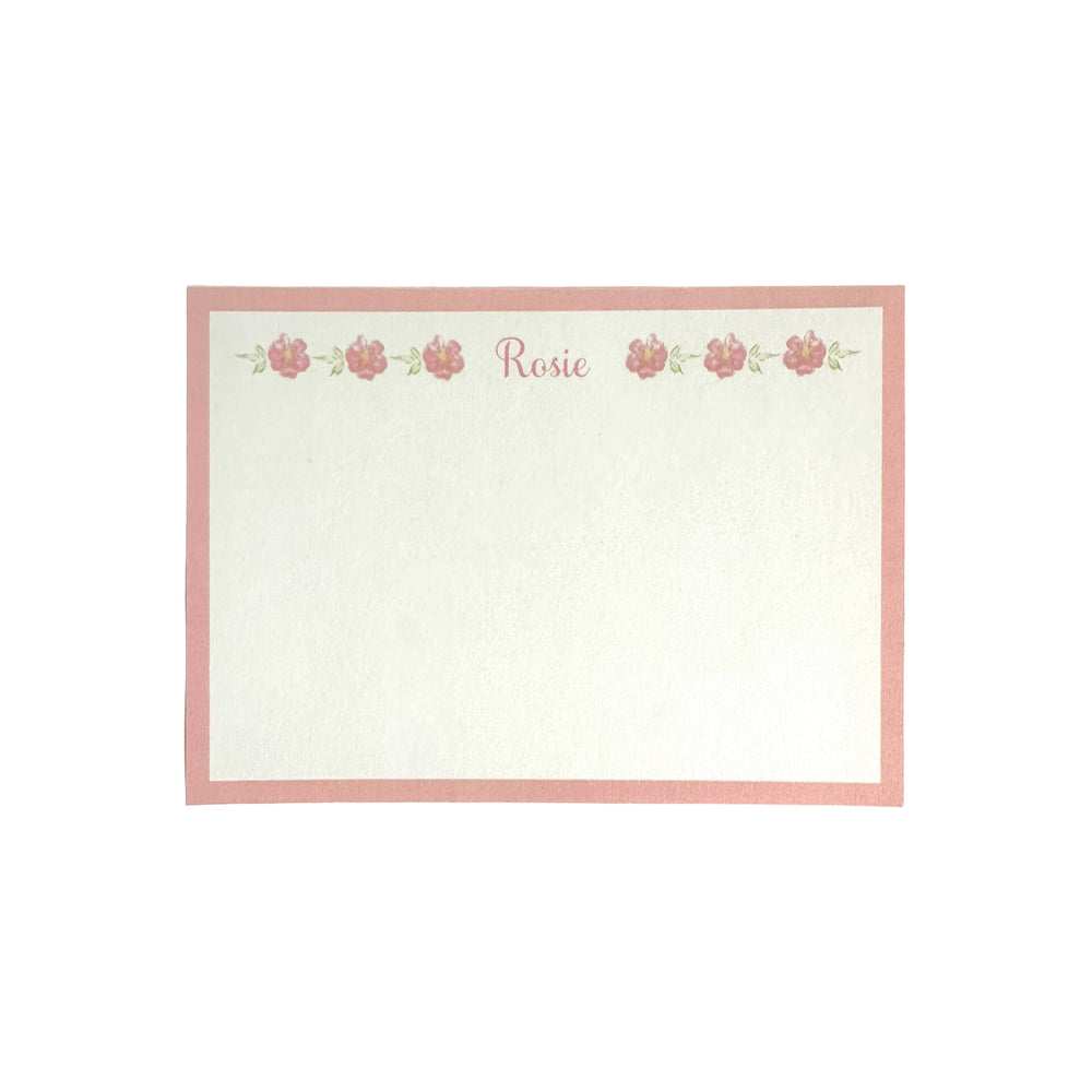 Flat view of floral notecard showing pink border, row of pink flowers and personalized name Rosie at top on off-white card stock