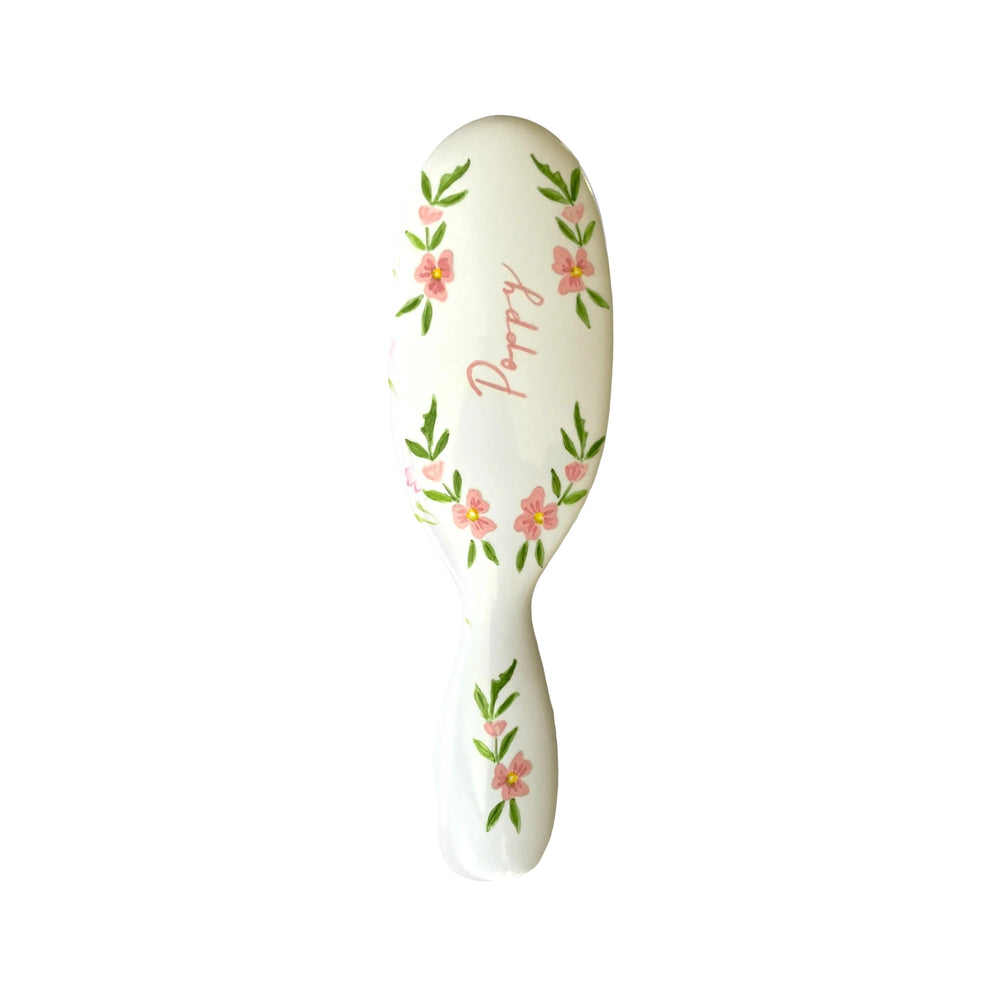 Top view of Mason Pearson Pocket child brush showcasing hand-painted pink poppy flowers and “Poppies” script on white background