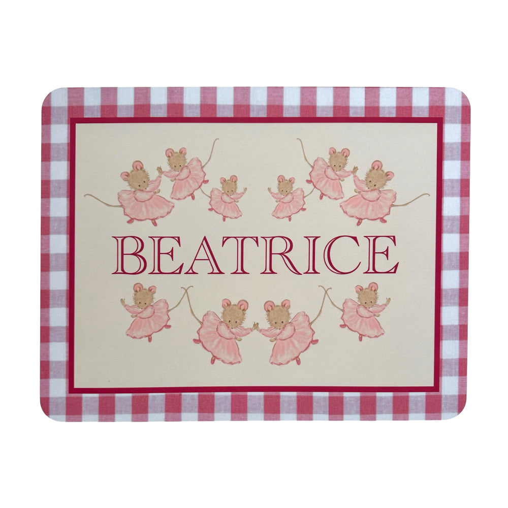 Top-down view of a personalized table mat reading BEATRICE with pink ballerina mice and a pink gingham border