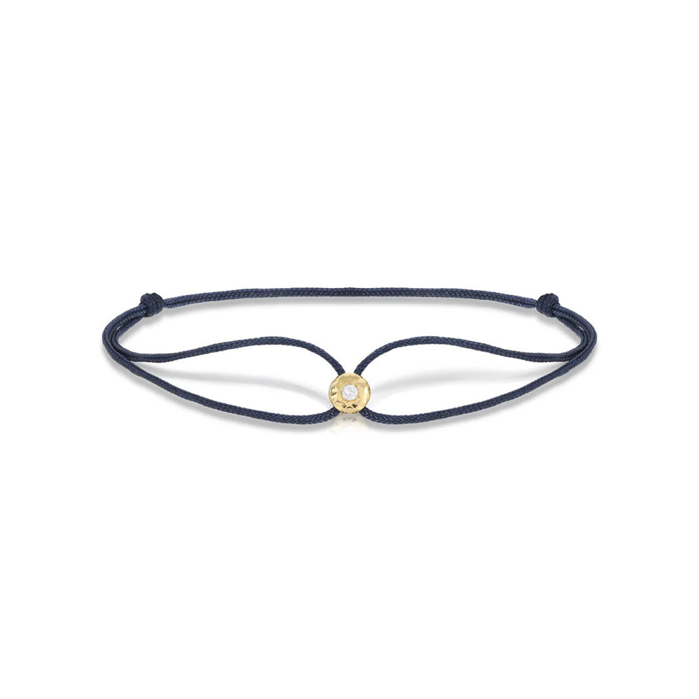 Top view of navy parachute bracelet showing adjustable navy cord and gold bezel with clear gem on white background