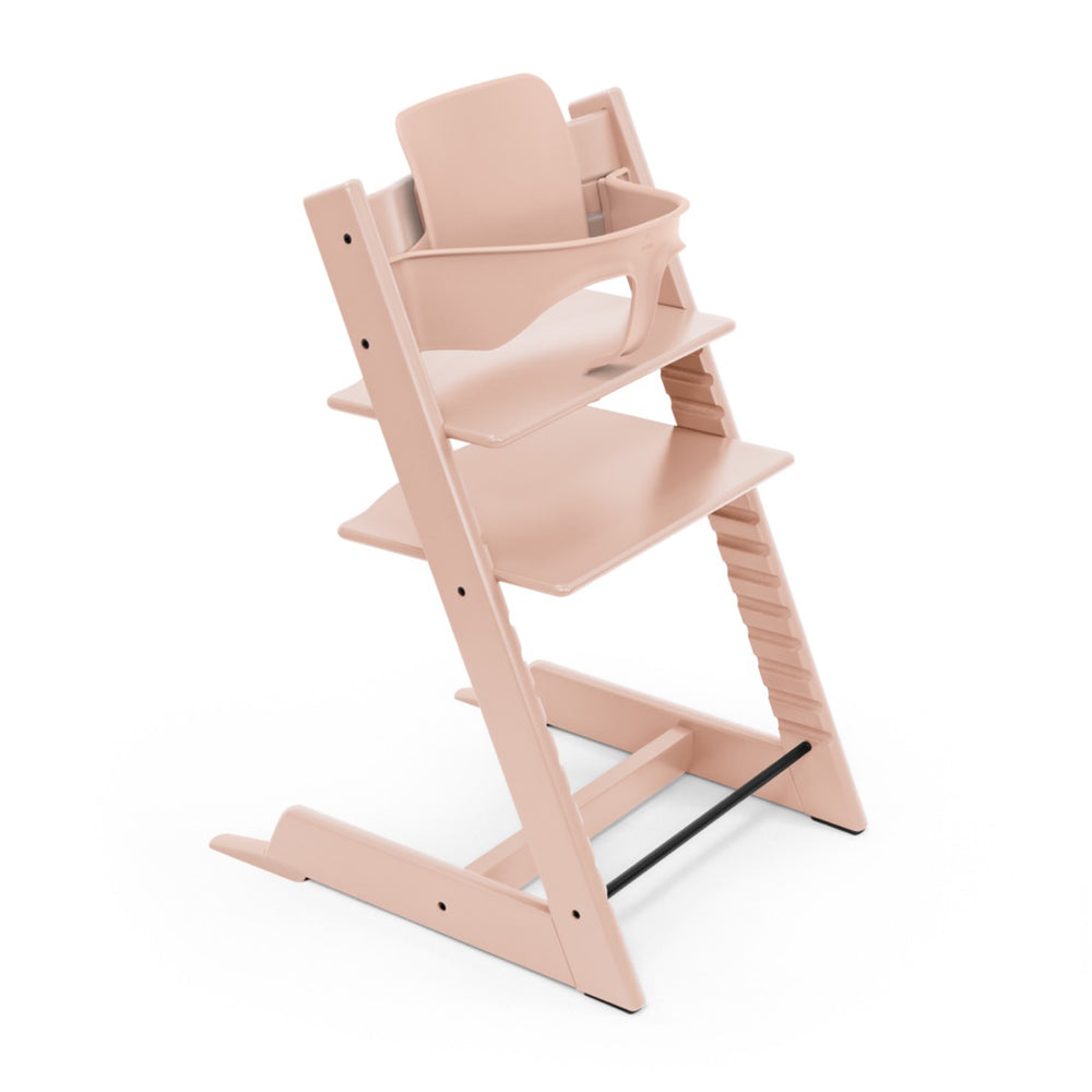 Angled view of Tripp Trapp Baby Set high chair in serene pink showing the baby seat insert and adjustable footrest on white background