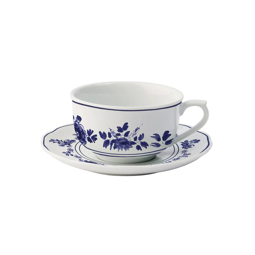 Three-quarter view of Gloria porcelain teacup and saucer showcasing blue floral pattern on white background