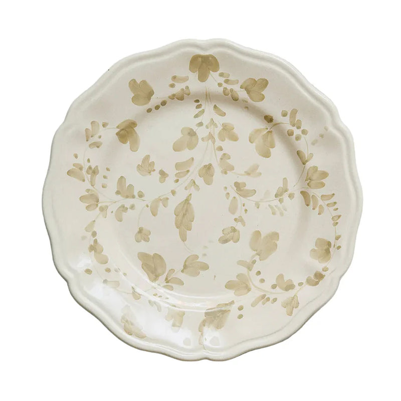 Top-down view of Flora dinner plate in ecru showcasing hand-painted floral motif and scalloped rim on white background
