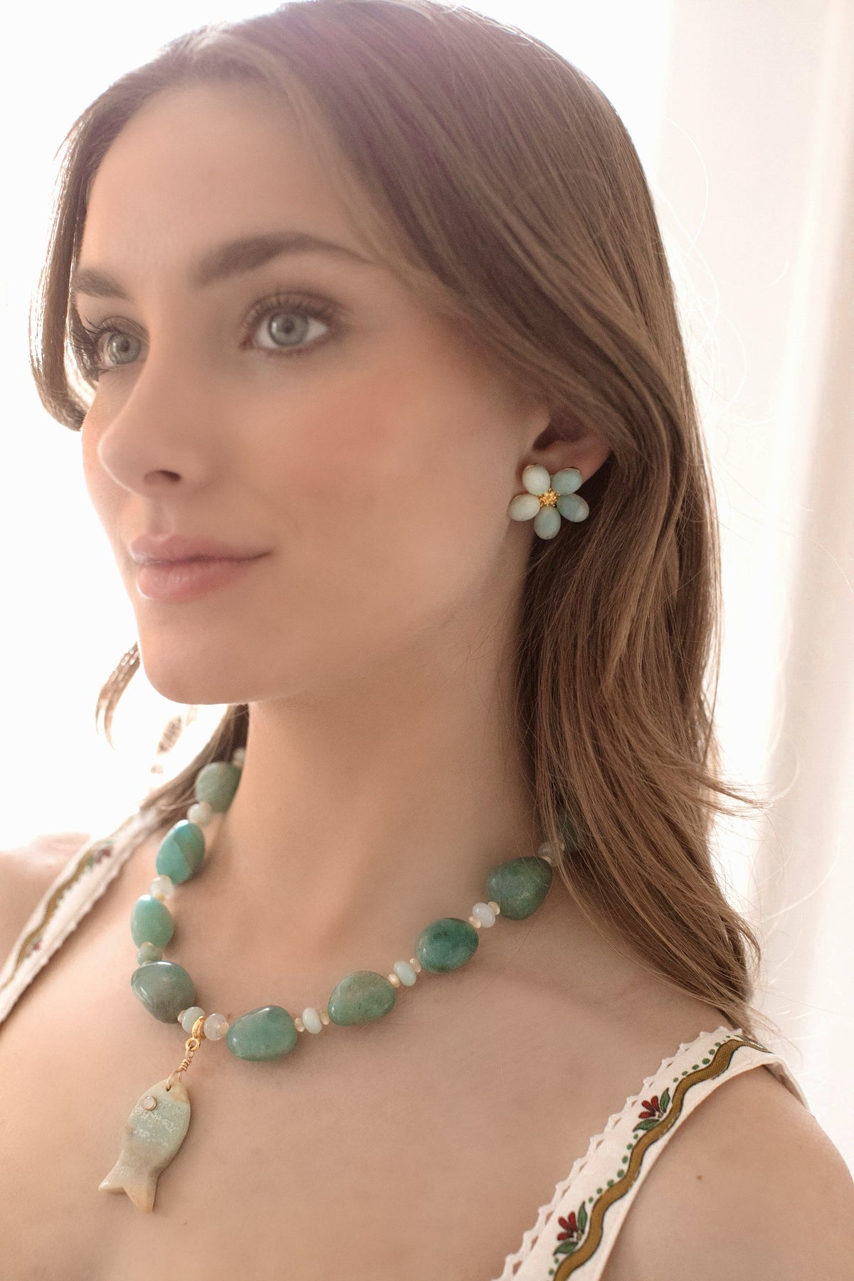 Three-quarter profile of Oahu Earrings showing amazonite flower studs with 24k antique gold-plated centers on a model