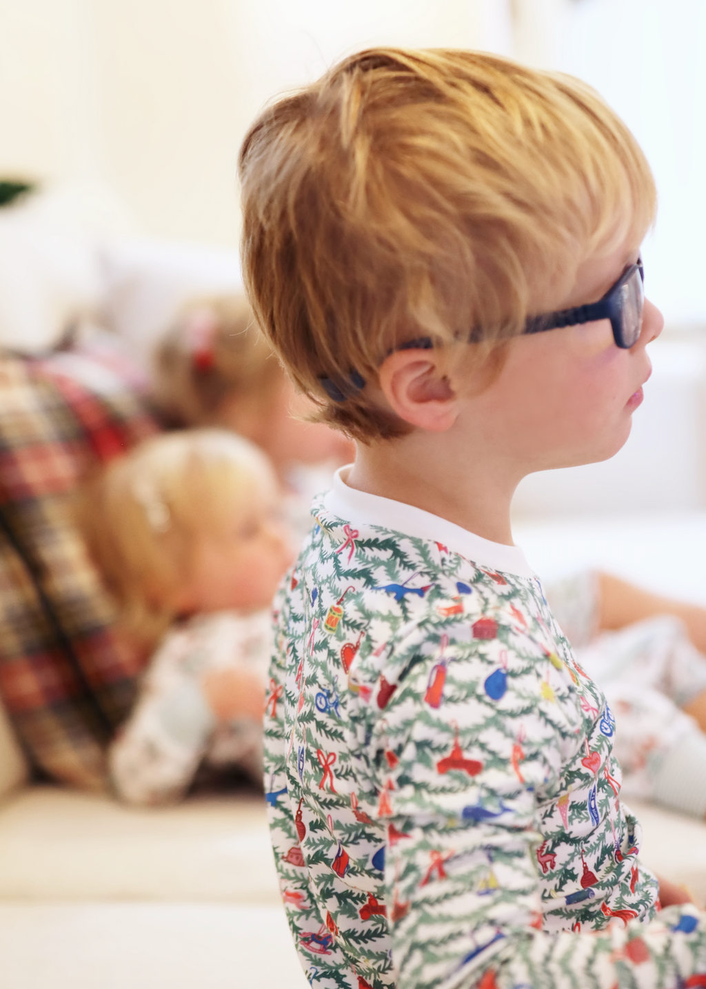 Side view of Oh Christmas Tree two-piece kids pajamas showing a Christmas block print on a child indoors