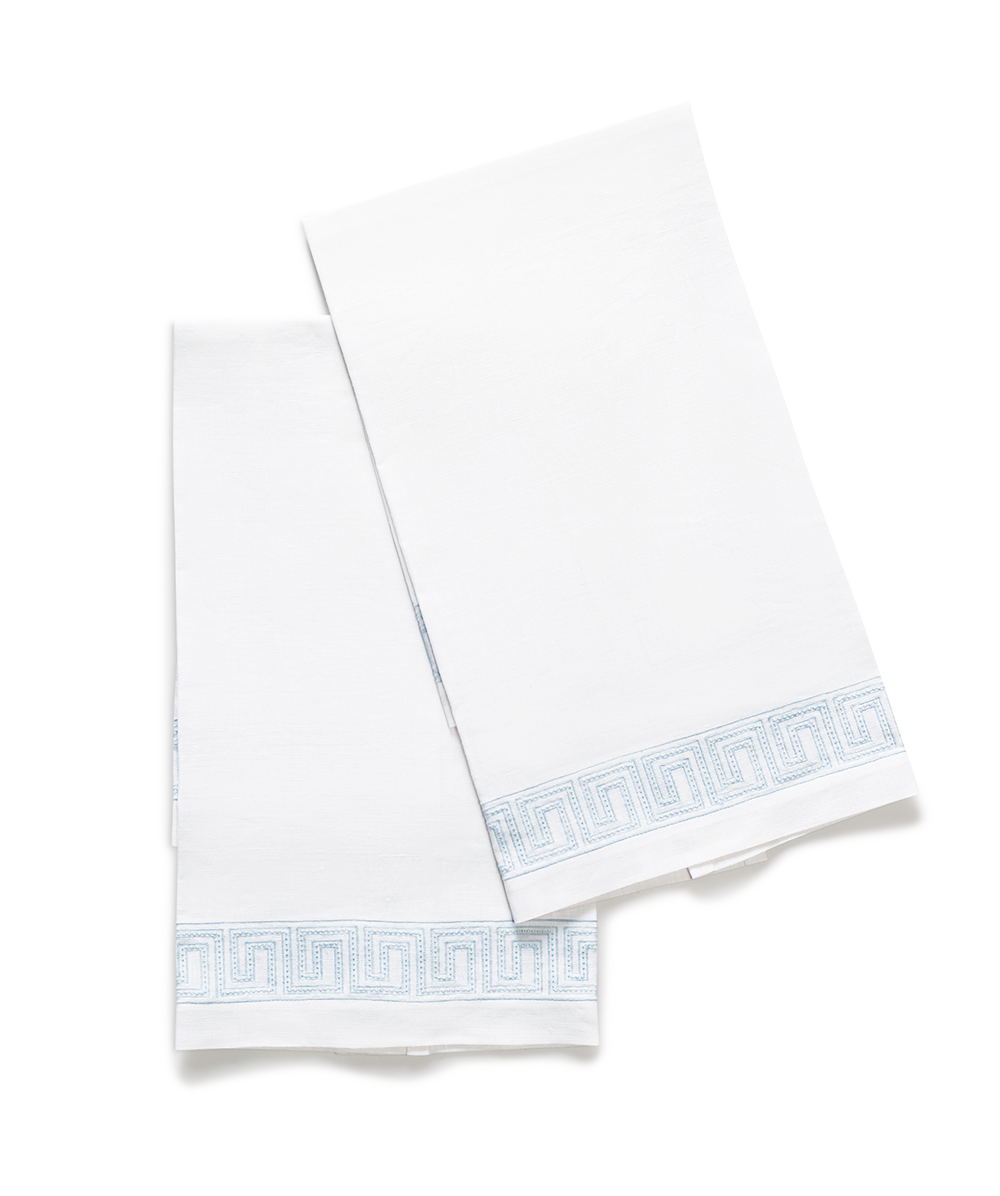 Flat-lay of Ophelia guest towels showing light-blue Greek key embroidery on white linen against white background