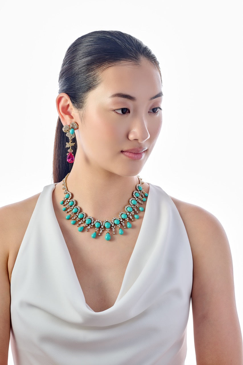 Three-quarter view of Orchid Orient earrings on model showcasing gold floral stud, turquoise beads and fuchsia teardrop against white background