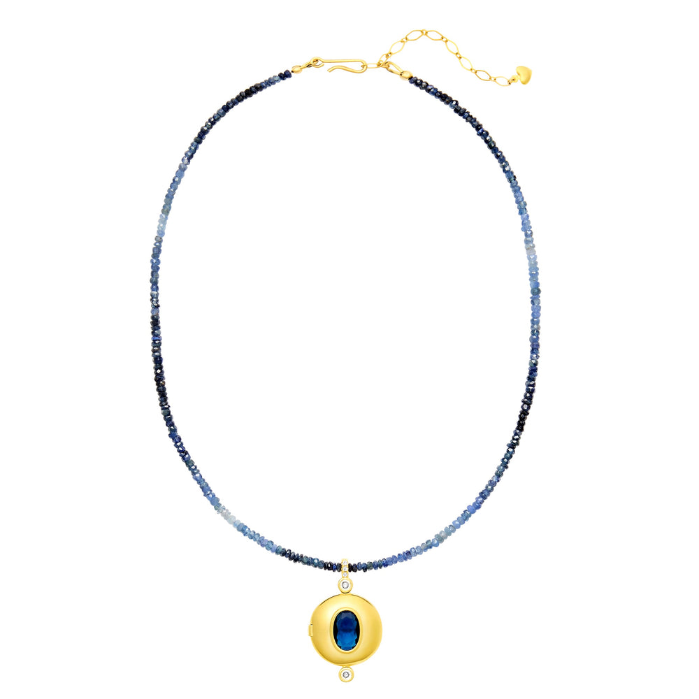 Flat-lay of Orion Necklace showcasing faceted blue ombre sapphire beads and gold-plated locket with blue stone on white