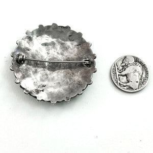 Back view of vintage sterling silver cluster pin showing its pin clasp and scalloped edge with a white background