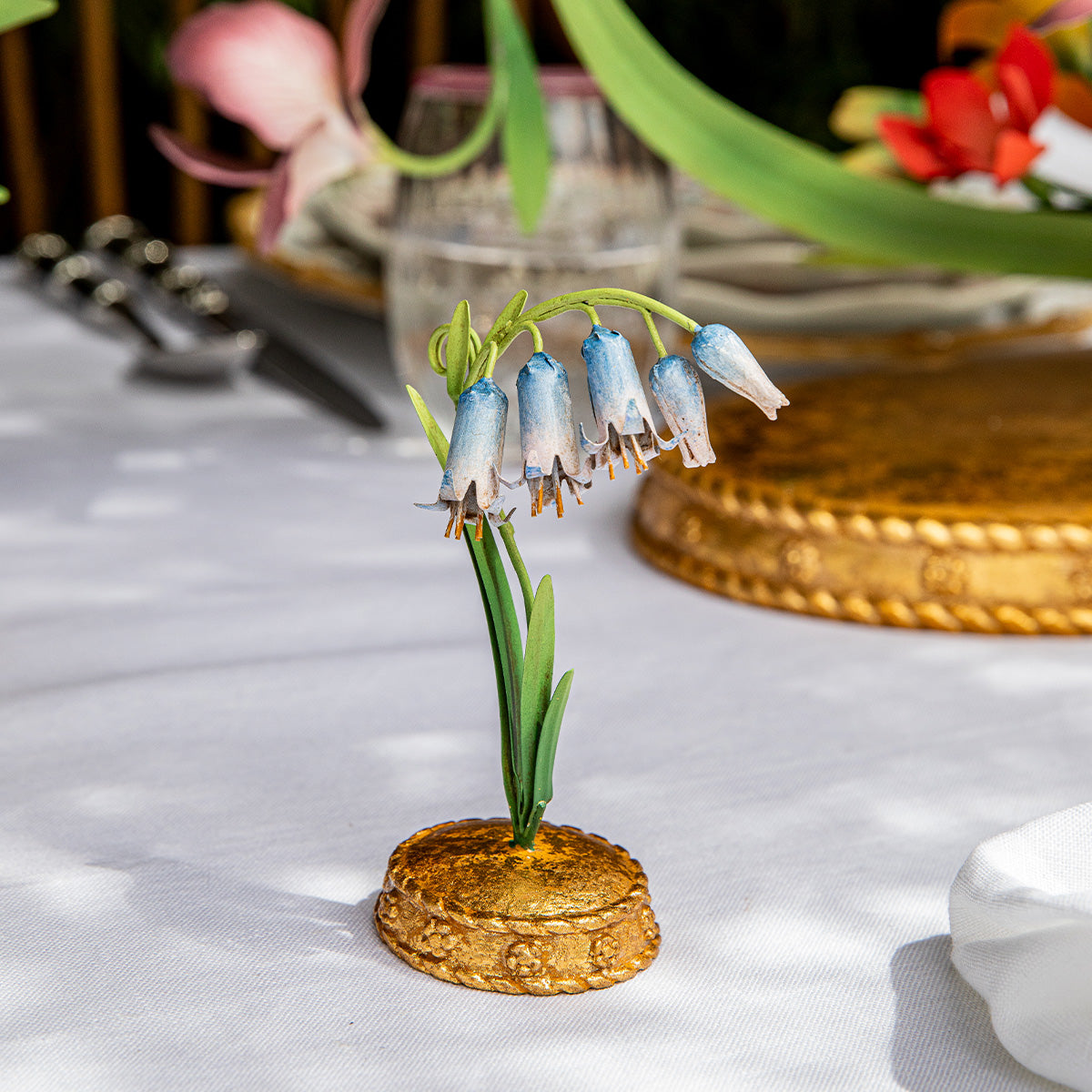 Front view of Meadow Walk Bluebell place card holder showing hand-painted bluebell flowers and gilded base on a white tablecloth