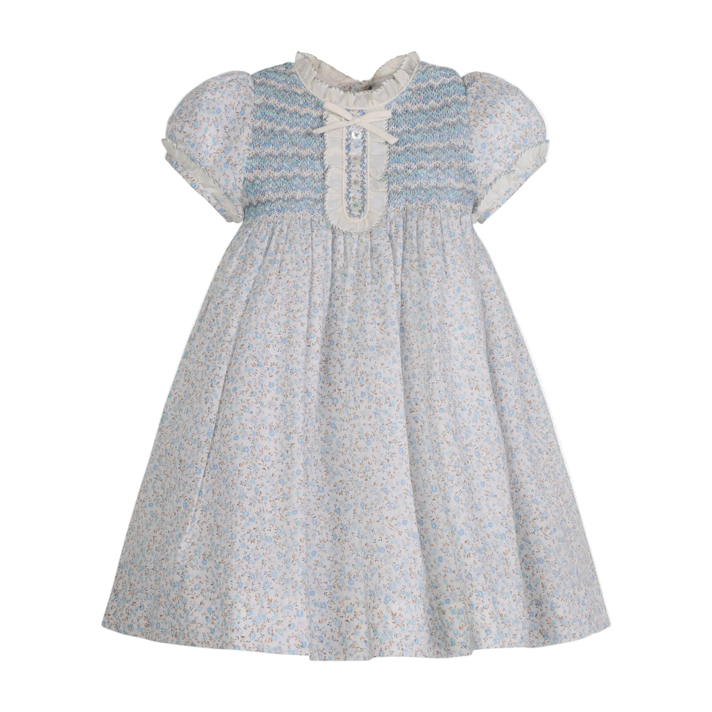 Front view of Clotilde Dress in blue showing zig-zag hand-smocked bib, ruffle neckline and puff sleeves on white background