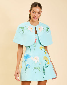 Promenade Embroidered Capelet in Blue Waltz moire with hand-sewn floral embroidery, crew neckline, and hook-and-eye closure.