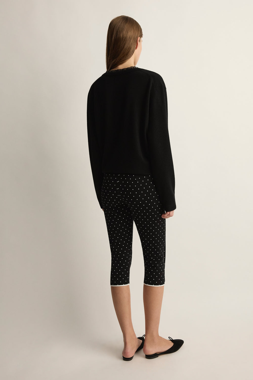 Rear view of Michalla Capri in black and white polka dot showcasing cropped length on model with neutral studio background
