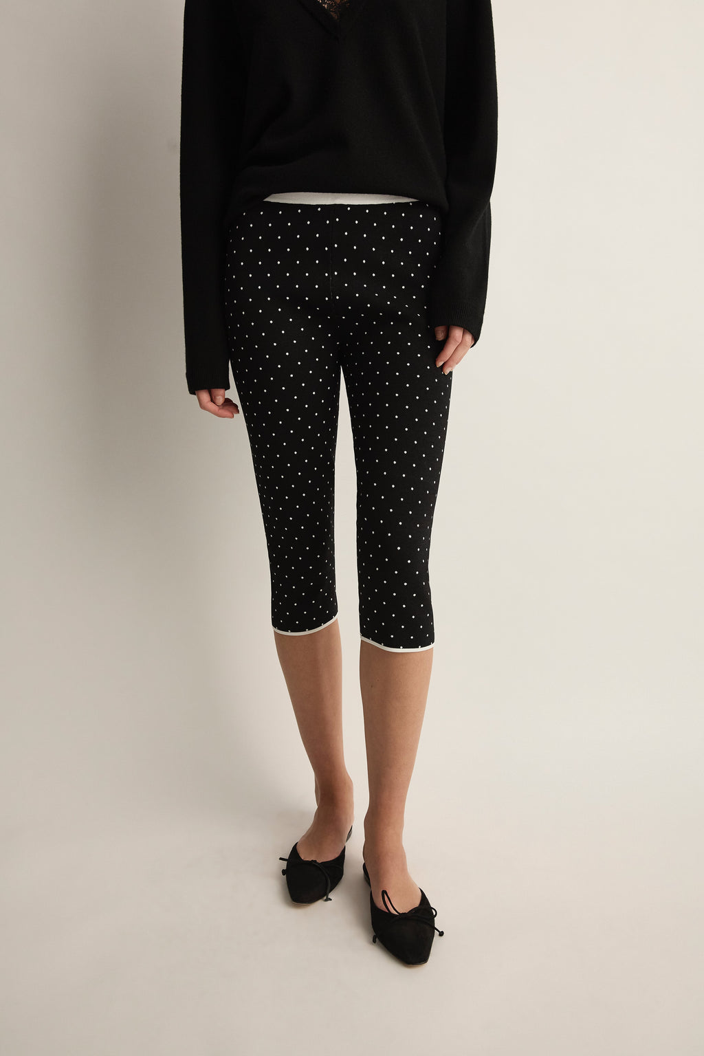 Front view of Michalla Capri in black and white polka dot showcasing cropped fit on model with neutral studio background