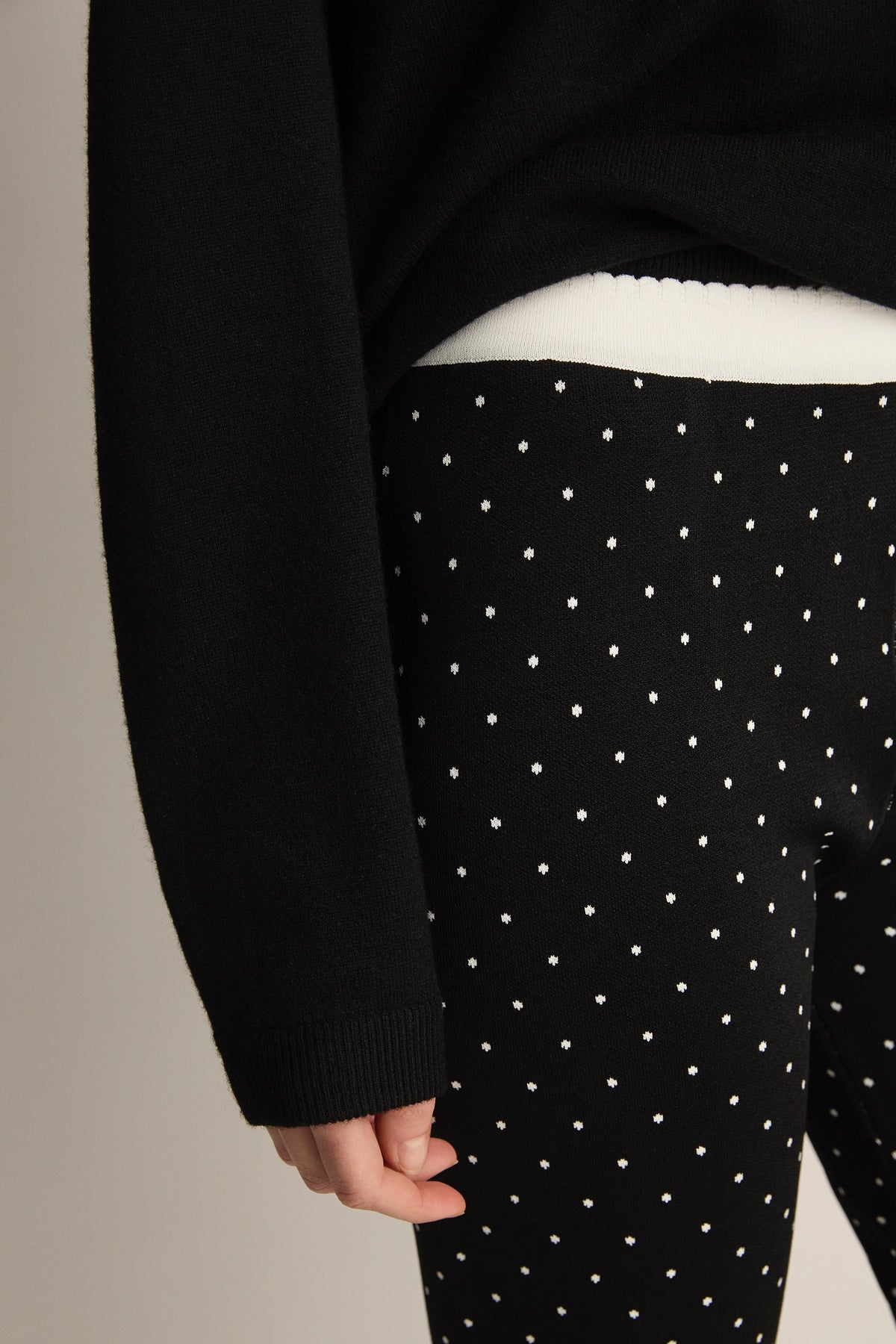 Close-up view of Michalla Capri showcasing black fabric with white polka dots on a model against a neutral background