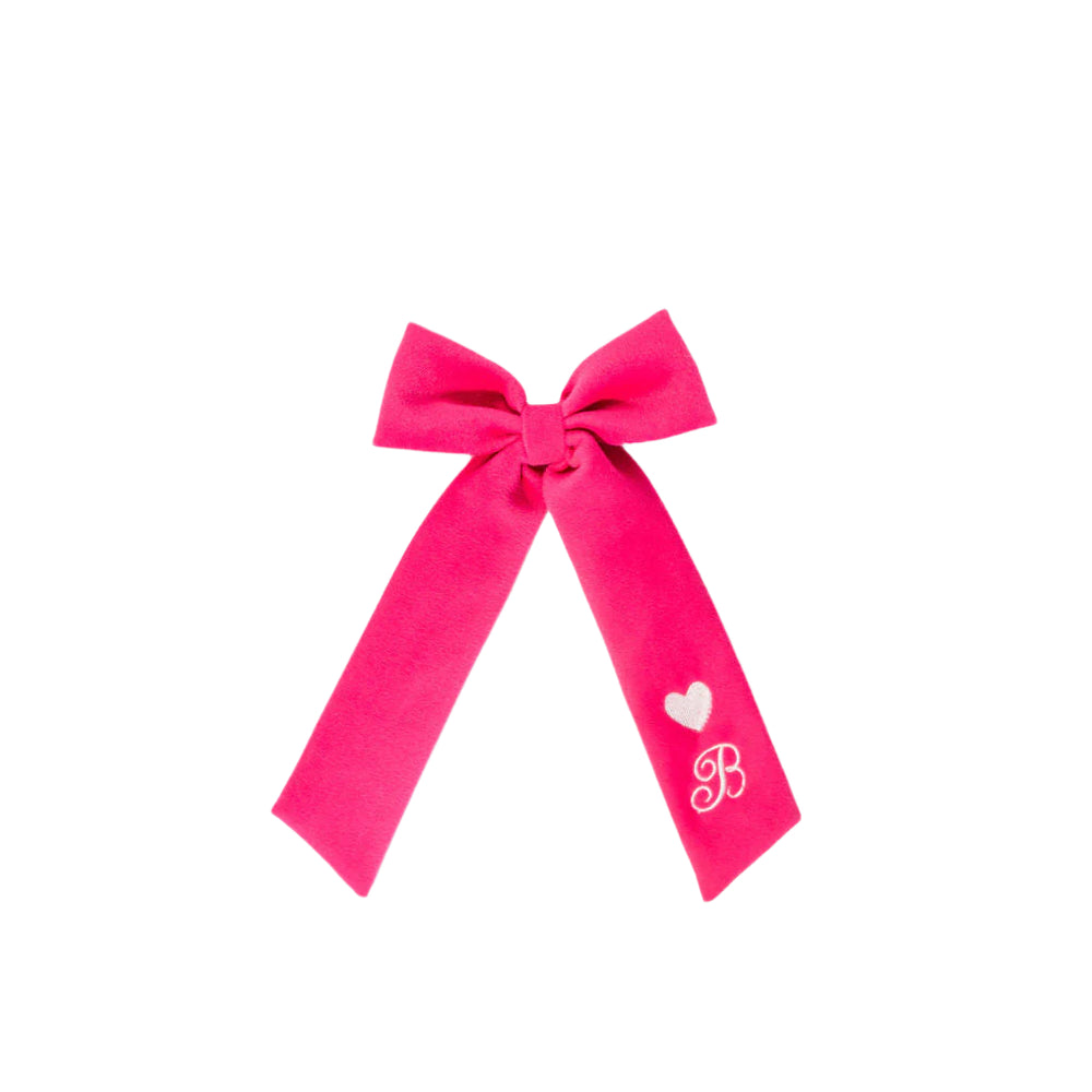 Front view of pink velvet hair bow with long tails showing embroidered heart and script initial B on white background