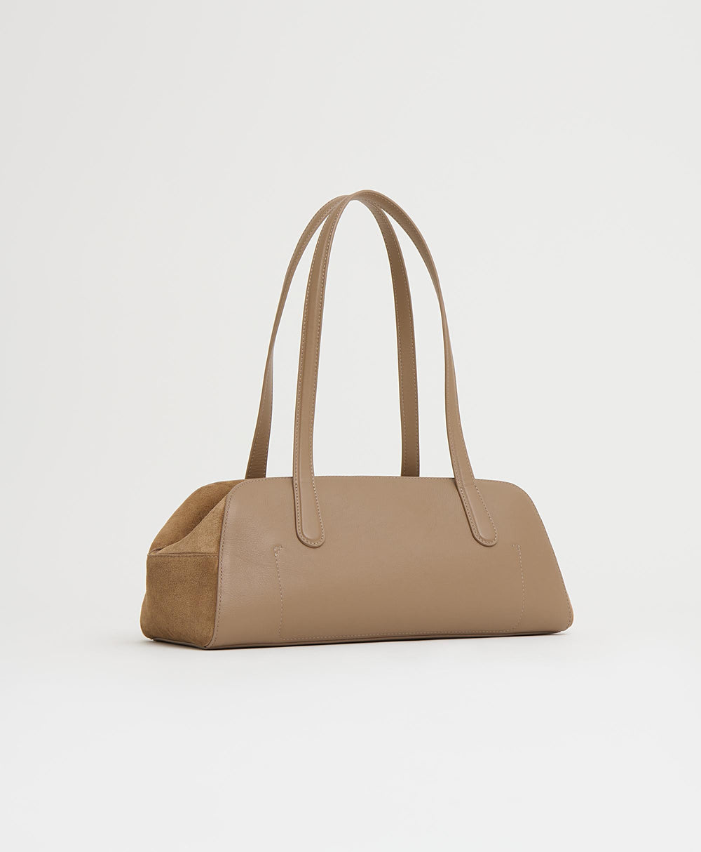 Three-quarter view of Helios shoulder bag in Anise showcasing elongated east-west silhouette, suede body, and long double straps on white background