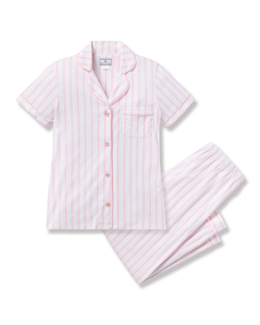 Petite Plume’s Womens Pima Crop Set in Pink and White Stripe features a luxurious pajama set with a vintage top, short sleeves, notched collar, and pink buttons on the front pocket. The matching pants have an elastic waistband,  all set against a white background.