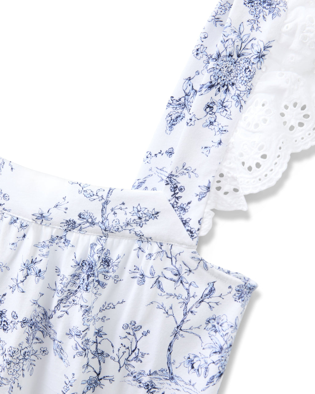 The Womens Pima Clara Short Set in Timeless Toile by Petite Plume showcases a blue floral pattern on white fabric. The strap, detailed with eyelet lace, adds botanical elegance and a delicate touch to the design.