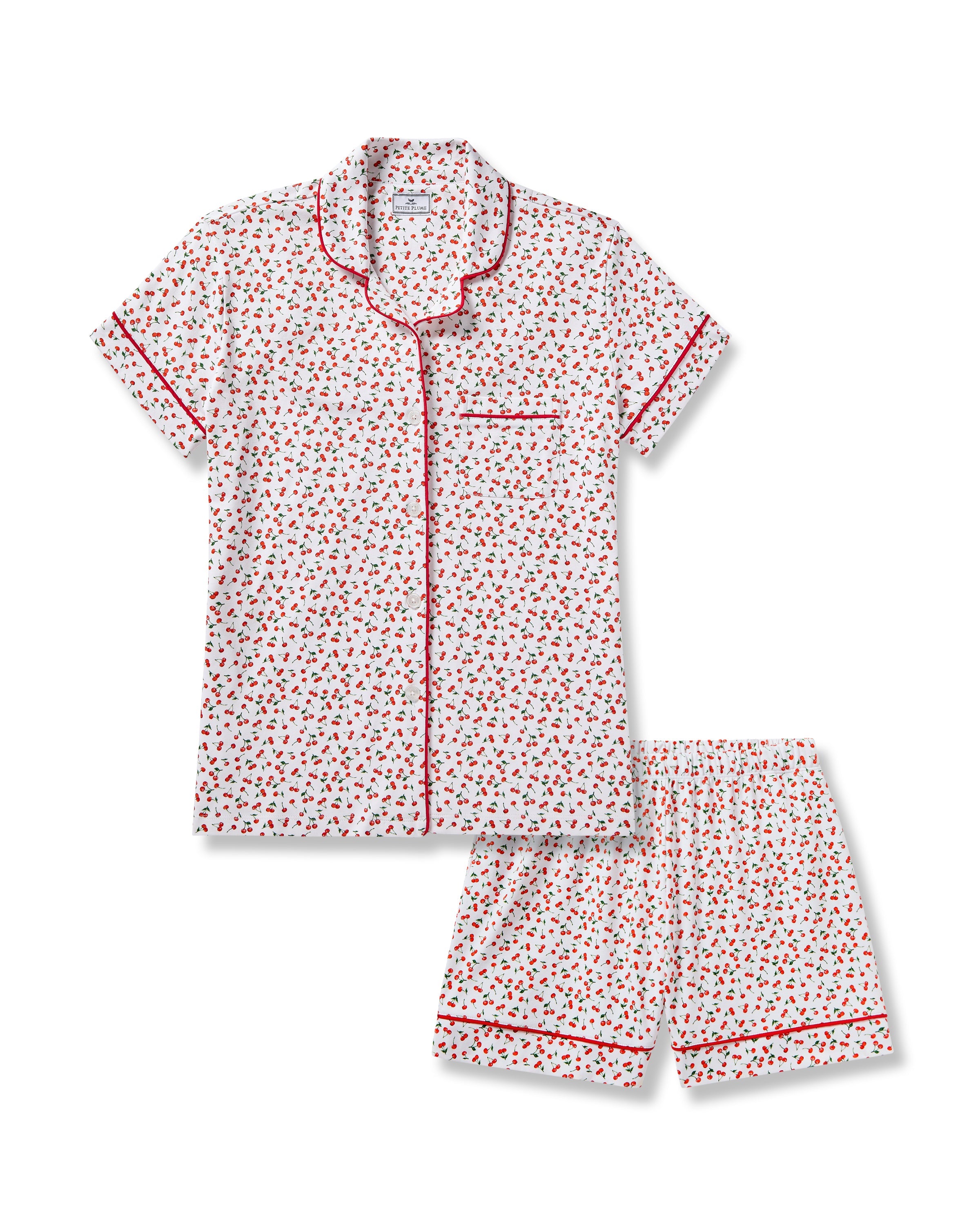 The Petite Plume Womens Pima Short Sleeve Short Set in Cherry Orchard features a white jersey knit with a cherry print, red piped collar, chest pocket, and matching shorts with an elastic waistband.