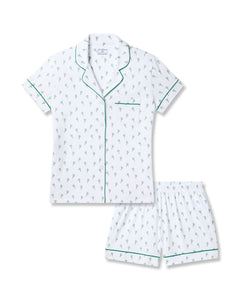 Petite Plumes Womens Pima Short Sleeve Short Set in Palmier features a white, palm tree-printed pajama set made from luxurious Peruvian Pima cotton. The button-up top includes a chest pocket and green piping, while the elastic-waist shorts also feature matching green piping for comfort and style.
