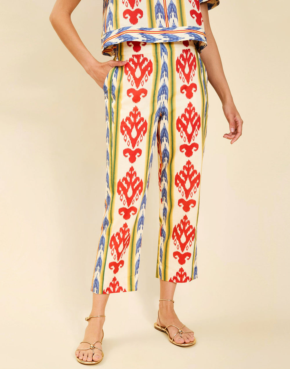 Woman wearing the Mestiza Palau Cigarette Pant in Ikat Sunrise print, featuring a slim-fit cigarette silhouette, front pleat detailing, cropped ankle-length fit, and lightweight linen fabrication.