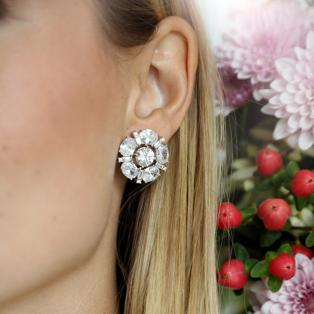 Close-up side view of Paley Stud in white gold showcasing clustered cubic zirconia stones on model’s ear with blurred floral background