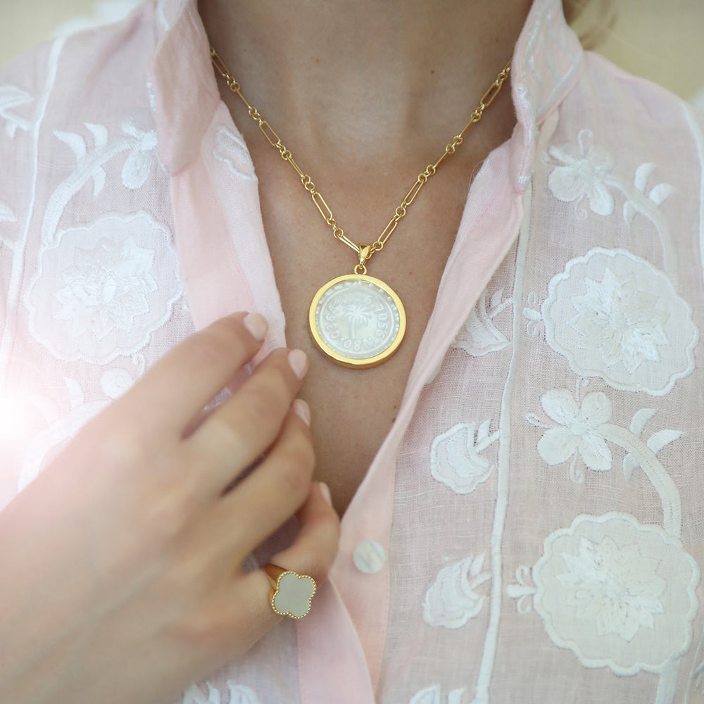 Close-up of Mixed Link Chain necklace showing alternating gold links and coin pendant on a model wearing a light pink blouse