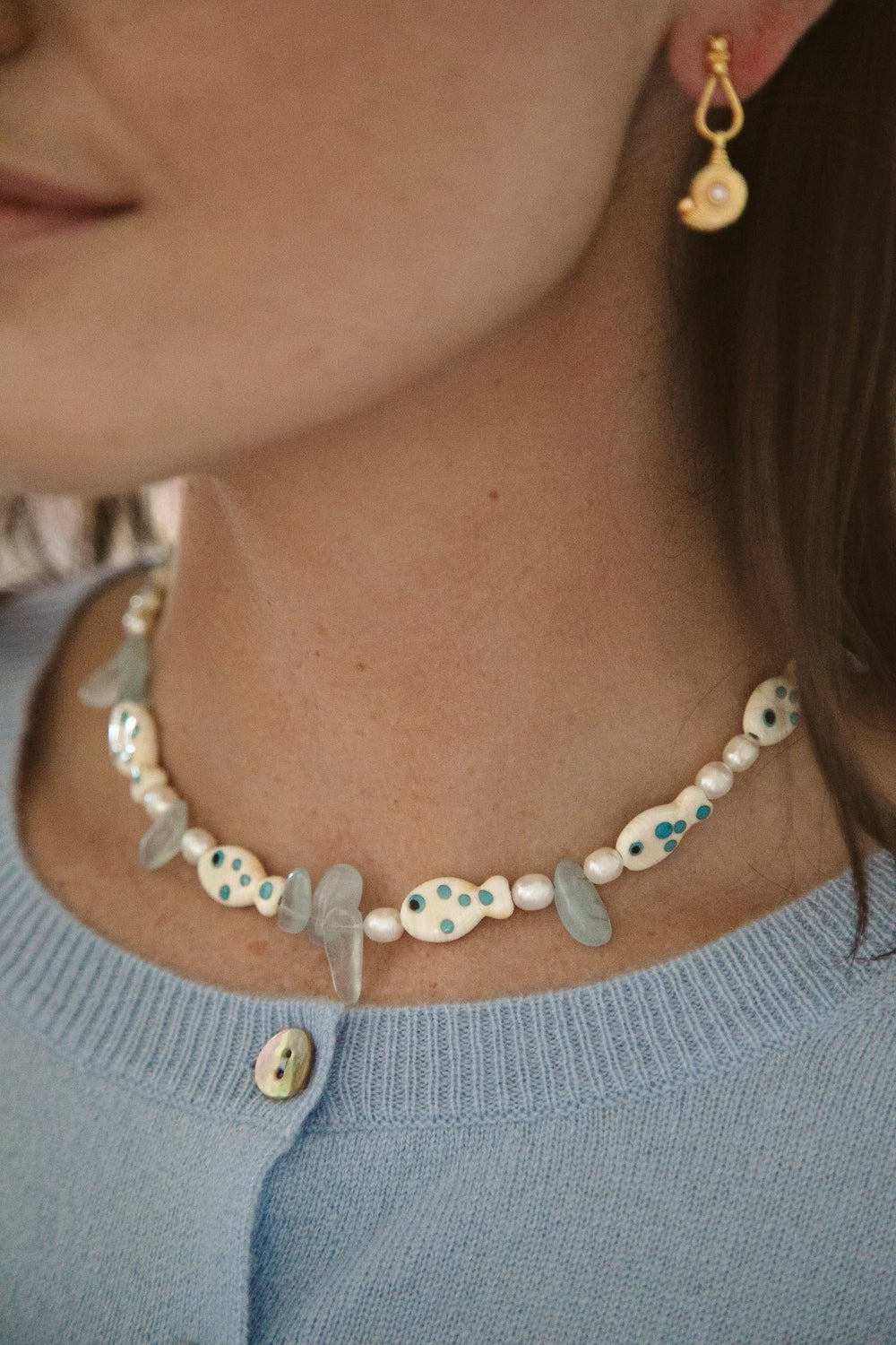 Close-up of Paros Necklace on model showing colorful lampwork glass fish, freshwater pearls, and aquamarine beads
