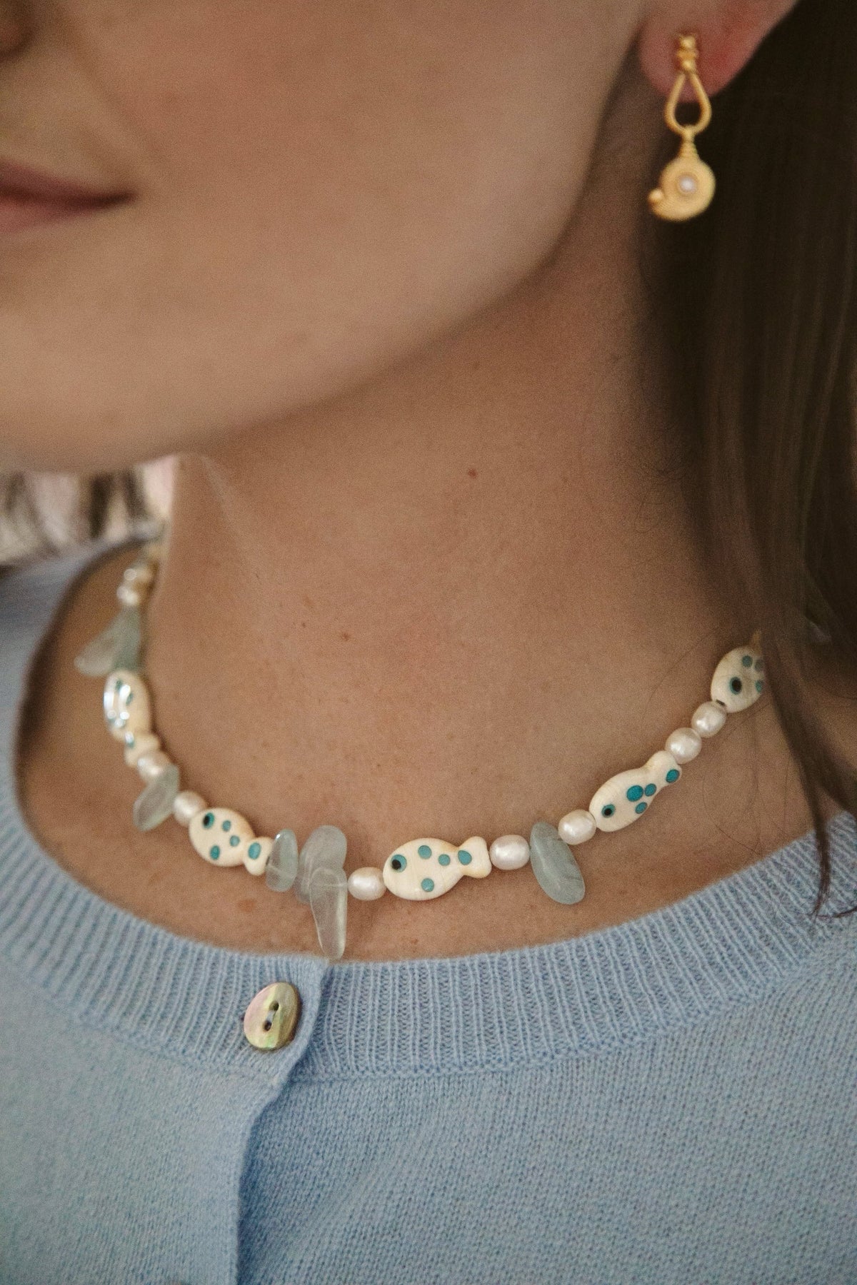 Close-up of Paros Necklace on model showing colorful lampwork glass fish, freshwater pearls, and aquamarine beads