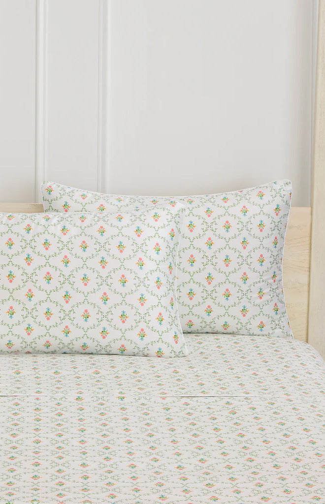 Front view of Pastel Trellis pillowcase set showcasing pastel floral trellis print on white brushed cotton sateen against a light paneled headboard