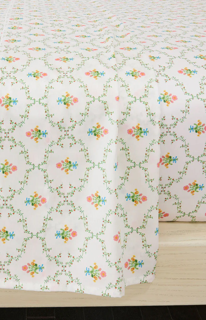 Close-up of Pastel Trellis top sheet showing pastel floral trellis pattern in pink, blue, and green on white, draped over bed edge