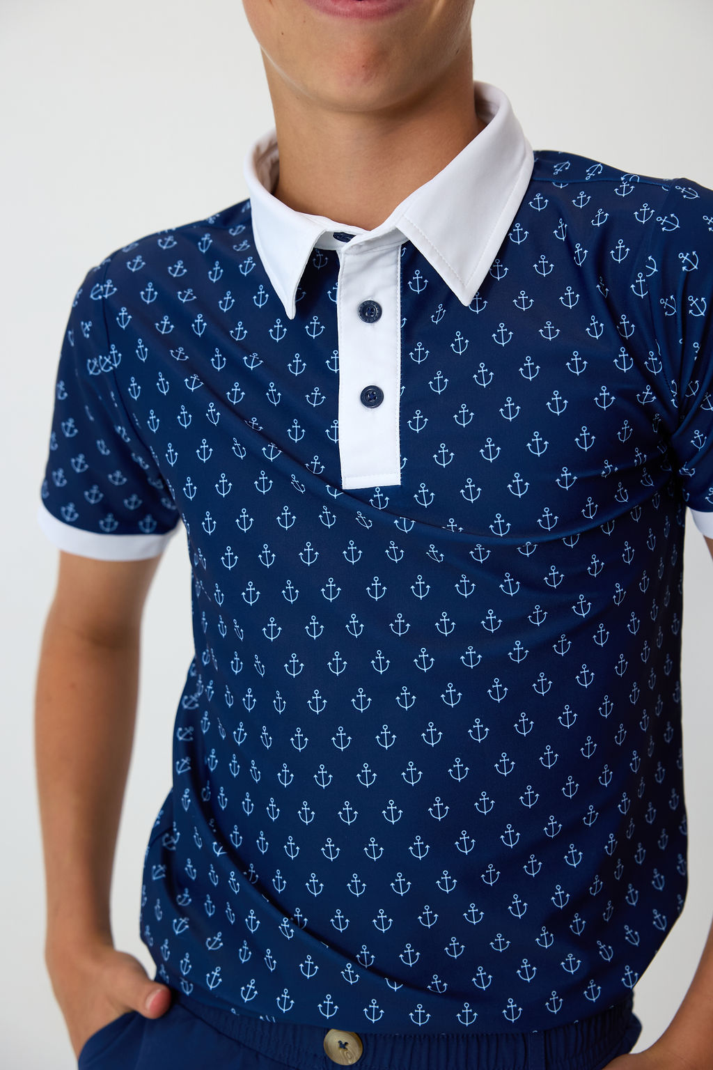 Front close-up of Anchor Polo Shirt on model; navy with all-over white anchor print and white contrast collar and placket