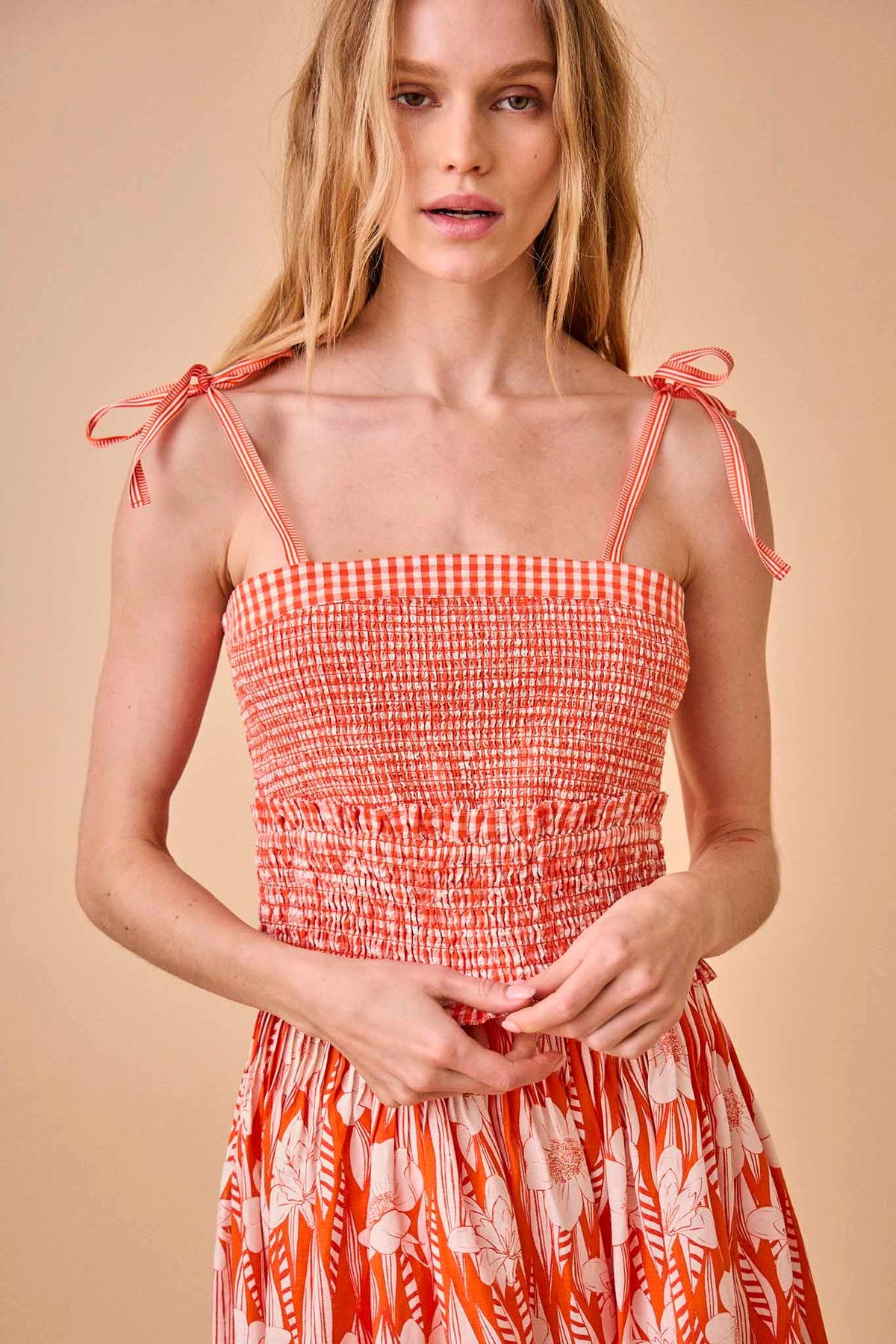 A square neck smocked top with tie shoulder straps in seersucker gingham with a ruffle hem.