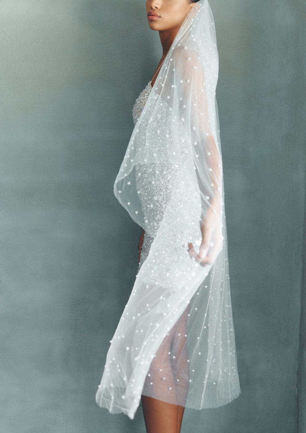 Side view of Perri veil on model showcasing beaded tulle with scattered pearls against a muted gray background