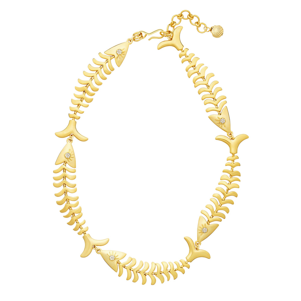 Flat lay of Pesca necklace with 24K antique gold plated articulated fish links and crystal eyes on white background