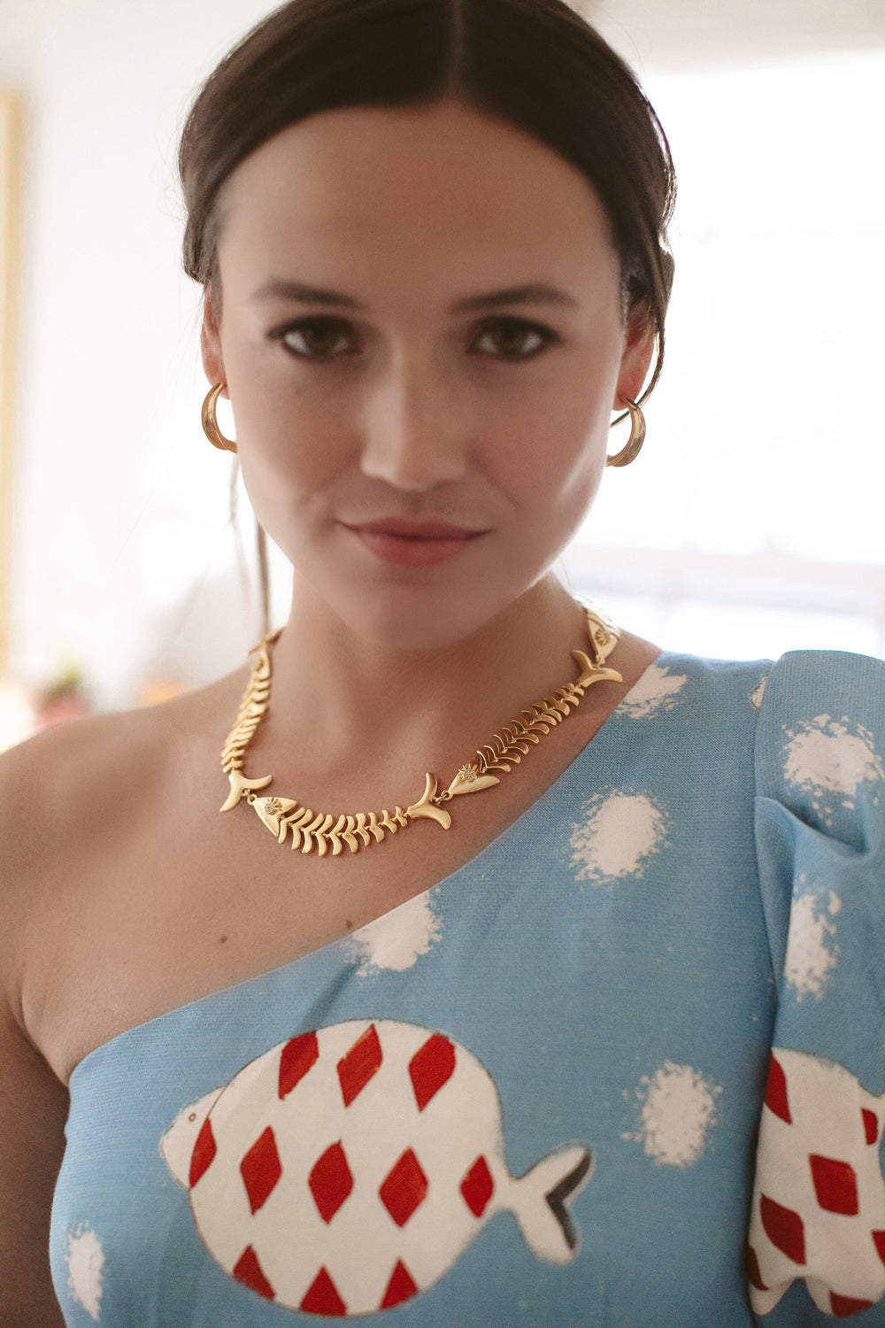 Close-up of Pesca Necklace on model, 24K antique gold-plated articulated fish chain with crystal eyes