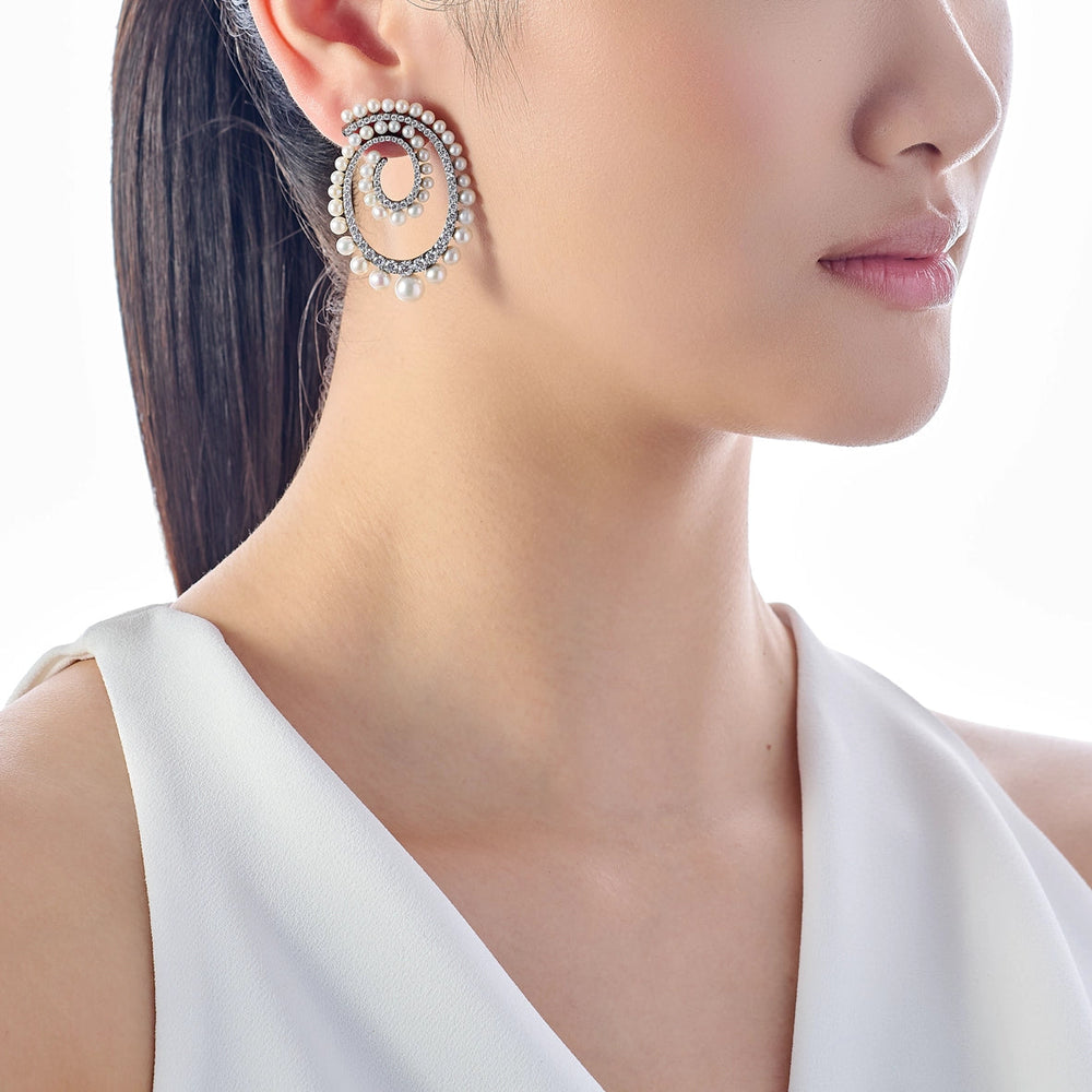 Side view of Petite Pearl Vortex Earrings on model showcasing spiral pearl and crystal hoop against white background