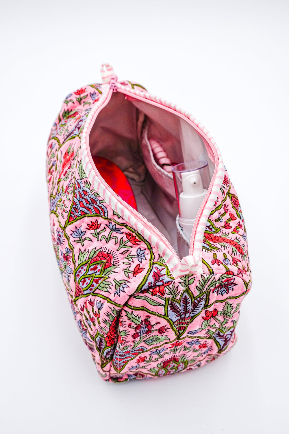Top-front view of Pink Arch toiletry bag showing pink floral block print and open interior pockets on white background