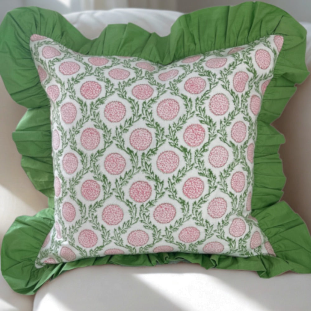 Decorative pillow with pink floral pattern and green ruffles on a white couch background