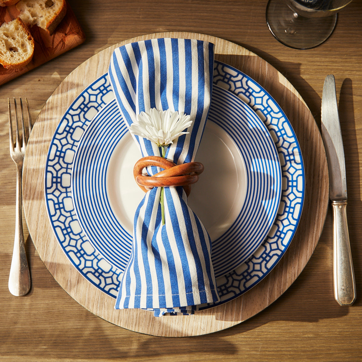 Top view of blue Pinstripe Dinner Napkins showcasing blue and white stripes on a place setting with plates and cutlery