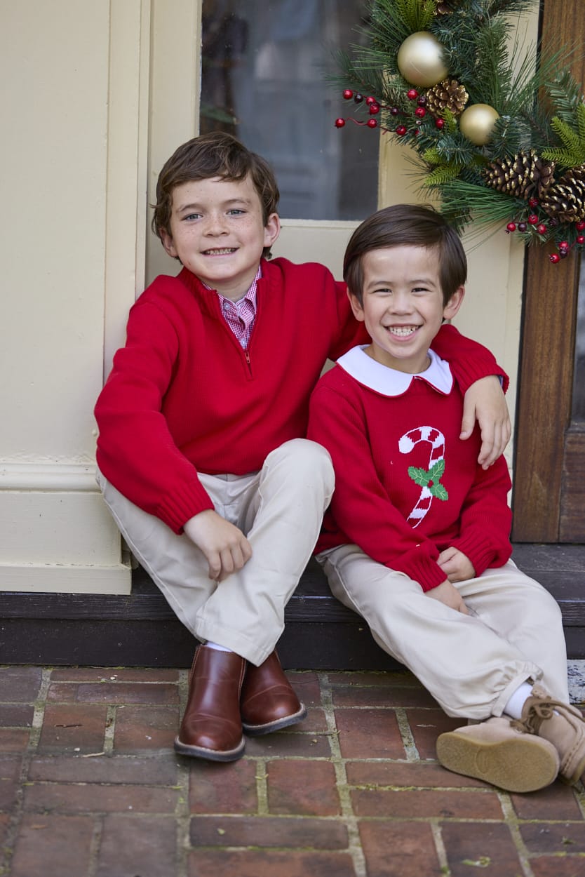 Little English traditional children's clothing. Red Intarsia Sweater with candy cane motif for boys and girls layered over red piped white knit peter pan shirt and khaki pebble twill banded pants. Older boys red quarter zip sweater and red gingham button down shirt and khaki pebble twill classic pants.