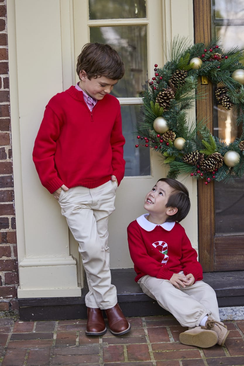 Little English traditional children's clothing. Red Intarsia Sweater with candy cane motif for boys and girls layered over red piped white knit peter pan shirt and khaki pebble twill banded pants. Older boys red quarter zip sweater and red gingham button down shirt and khaki pebble twill classic pants.