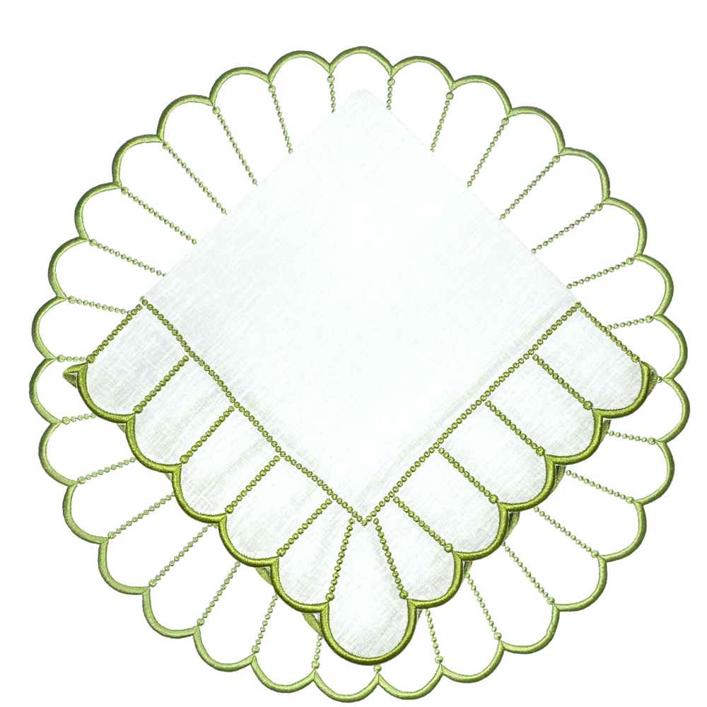 Overhead view of Pippa placemat and napkin set showcasing scalloped green embroidered edge and linen texture on white background