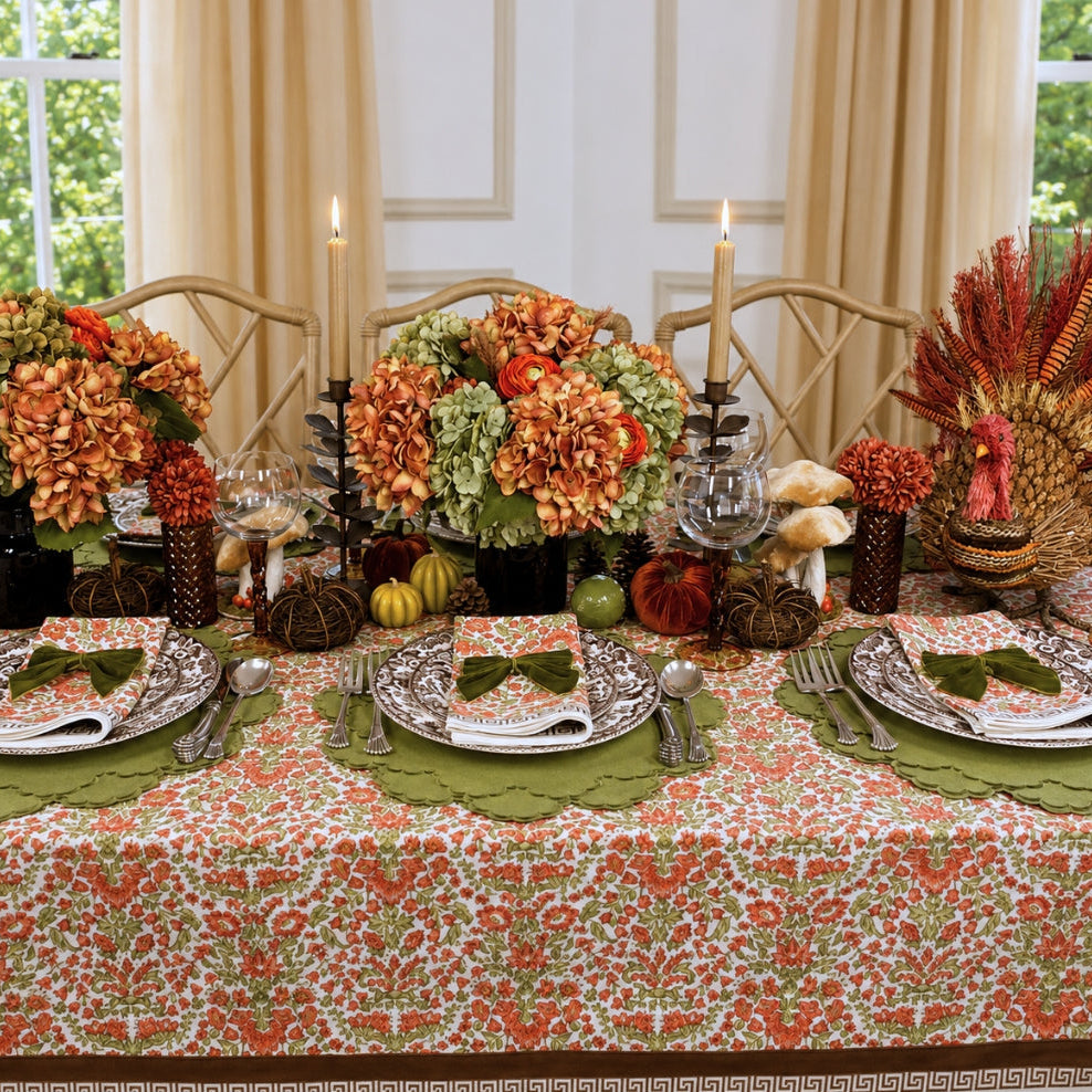 A hand block printed tablecloth, featuring a floral pumpkin and sage green floral pattern on a white background, finished with a brown band and Greek key border at the bottom, Thanksgiving tablecloth, luxury table linens