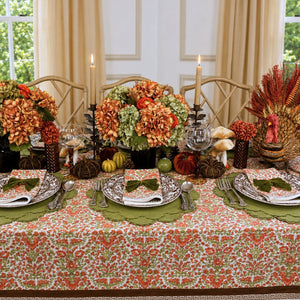 A hand block printed tablecloth, featuring a floral pumpkin and sage green floral pattern on a white background, finished with a brown band and Greek key border at the bottom, Thanksgiving tablecloth, luxury table linens