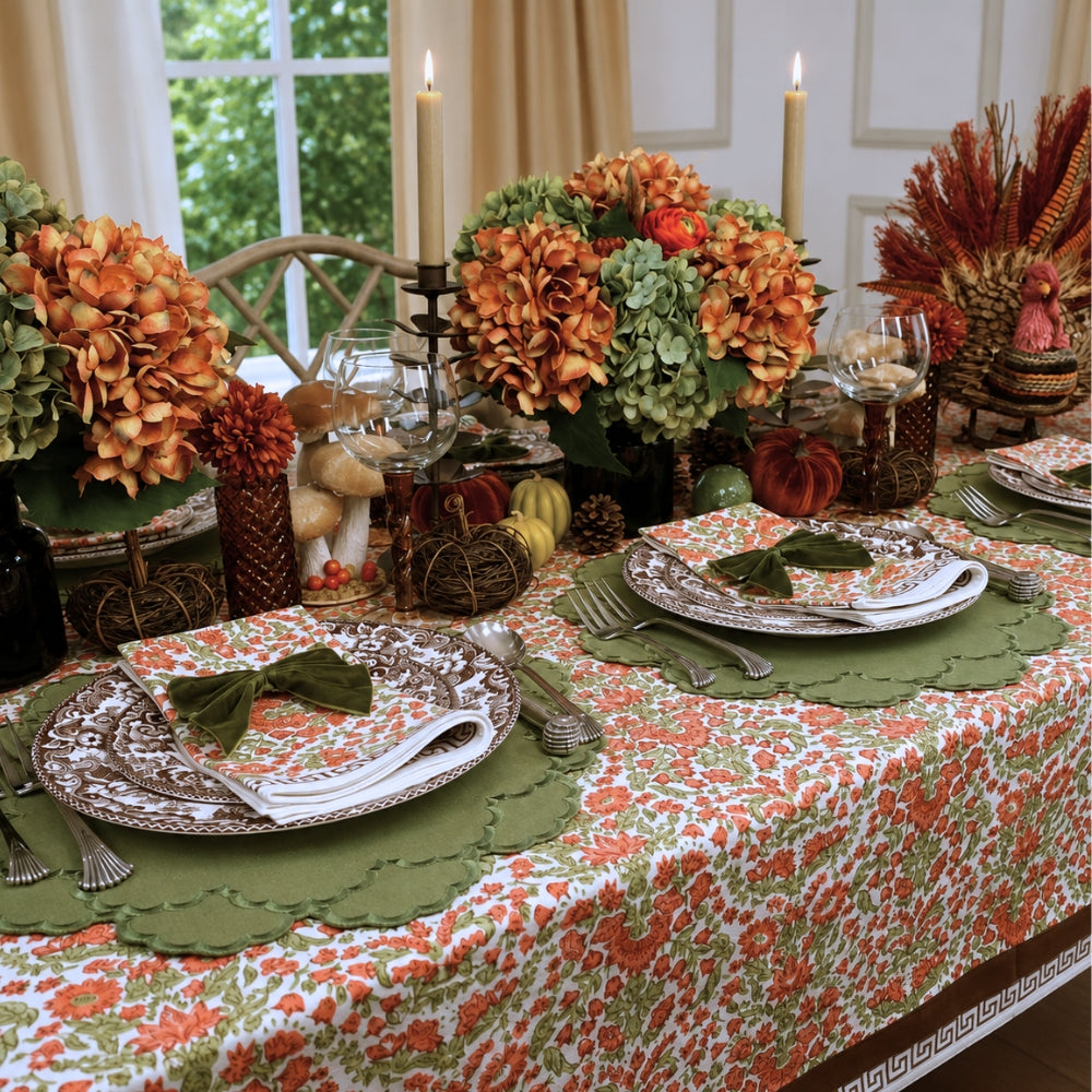A hand block printed tablecloth, featuring a floral pumpkin and sage green floral pattern on a white background, finished with a brown band and Greek key border at the bottom, Thanksgiving tablecloth, luxury table linens