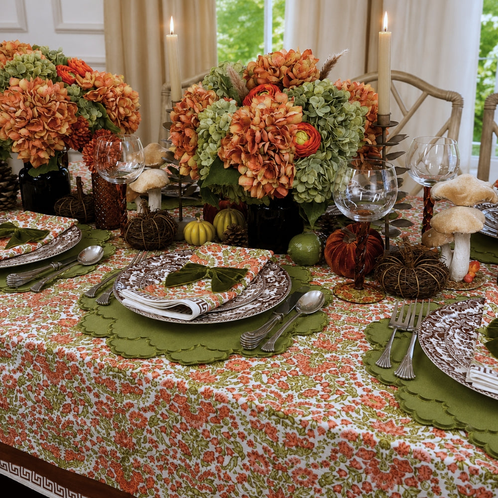 A hand block printed tablecloth, featuring a floral pumpkin and sage green floral pattern on a white background, finished with a brown band and Greek key border at the bottom, Thanksgiving tablecloth, luxury table linens